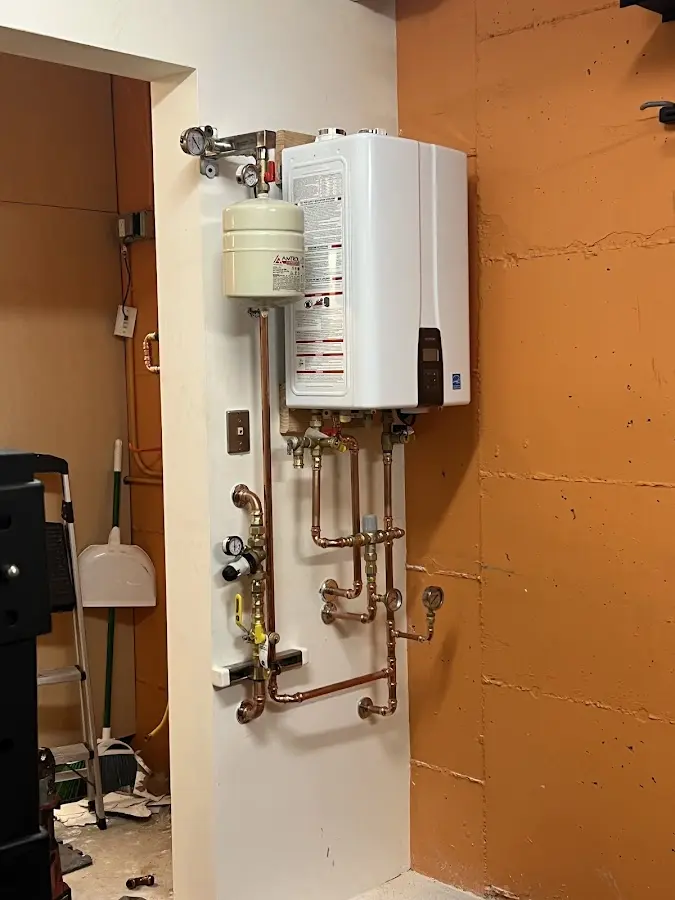 Plumbing technician inspecting water heater connections in Red Rock